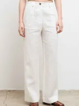 Pantalón de lino blanco de corte recto con cintura alta y detalles de botones.
