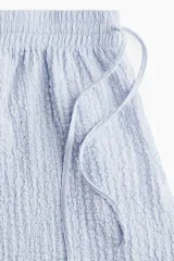 Short celeste de punto arrugado con cintura elástica y cordón ajustable.