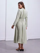 Vestido maxi color beige, con cuello mao, mangas 3/4 con presilla y lazo en la cintura.