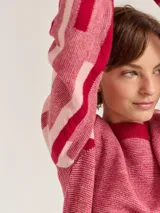 Buzo de lana color rojo y rosa con diseño moderno en las mangas, que proporciona calidez sin sobrecalentar.