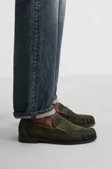 Mocasín color marrón de cuero con acabado serraje, antifaz, horma redonda y suela con ligero tacón.
