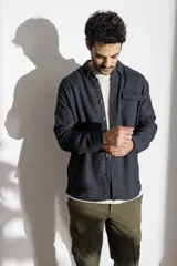 Camisa tipo chaqueta azul marino con textura de espiga, cuello clásico, cierre frontal con botones, manga larga y bolsillo de parche en el pecho.