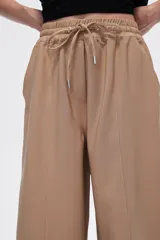 Pantalón negro ancho de viscosa con vivos laterales en blanco, dorado y marrón.