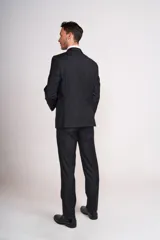 Traje de vestir azul marino, compuesto por saco de dos botones con solapa de muesca, dos bolsillos laterales con solapa y un bolsillo de ojal en el pecho, y pantalón de vestir con corte recto. Incluye camisa blanca, corbata celeste y pañuelo de bolsillo blanco con borde celeste.