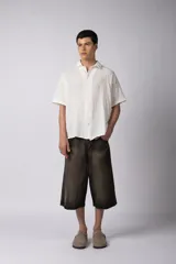 Camisa blanca de lino con cuello clásico, manga corta y cierre frontal con botones.