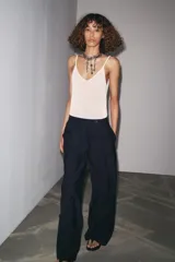 Pantalón de tiro medio color celeste confeccionado en hilatura con mezcla de lyocell. Tiene bolsillos laterales, pinzas delanteras, pierna ancha y cierre frontal con cremallera y botón.