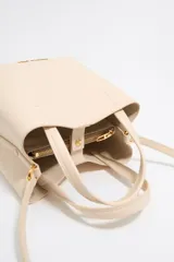 Bolso tote pequeño de cuero sintético color negro con doble asa de mano y correa bandolera ajustable y extraíble. Logotipo de la marca en letras doradas en la parte frontal.