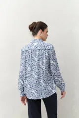 Camisa de manga larga con estampado paisley en tonos azul y blanco, cuello camisero y cierre frontal con botones.