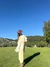 Ruana color crema tejida en lana merino, con flecos y bolsillos frontales.