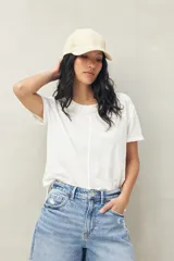 Remera blanca de manga corta confeccionada en algodón liviano con textura levemente jaspeada. Presenta tajos laterales y costura central al frente.