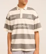 Camisa polo oversized con cuello abotonado, mangas cortas y diseño a rayas horizontales en tonos crema y gris. Presenta estampados con texto en el pecho.