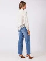 Camisa de algodón color naranja, con bordado suizo y encaje calado. Tiene cuello con solapa, botones frontales, mangas largas con terminación de encaje y ruedo asimétrico con galón de encaje.