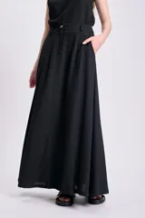 Falda larga negra de lino, corte recto y bolsillos laterales.