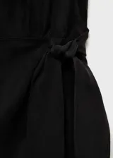 Vestido midi negro de tejido fluido con tirantes anchos, cuello escotado y detalle de nudo en la cintura.