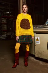 Sweater de lana amarillo con aplique circular de lana marrón en el frente. Corte holgado, cuello redondo y puños acanalados. 