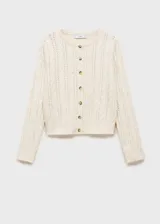 Cárdigan color crema de tejido de punto grueso con diseño trenzado y calado. Tiene cuello redondo, cierre frontal con botones y mangas largas.