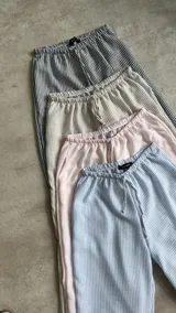 Pantalón holgado a rayas verticales en tonos gris y blanco, con cintura elástica ajustable mediante cordón.