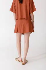 Minifalda color ladrillo con rayas verticales finas y botones dorados en el lateral.