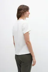 Remera blanca con bordados de palmeras, de corte clásico y manga corta.