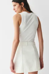 Minifalda evasé de denim color blanco, de tiro alto con botonadura frontal y bolsillos decorativos con solapa y botón.