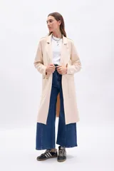 Blazer largo de mujer, color beige claro, con solapas amplias, bolsillos frontales grandes y corte recto.