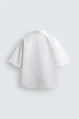 Camisa blanca de corte boxy fit, confeccionada en tejido técnico con algodón, de manga corta y cuello solapa.