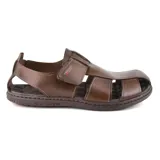 Sandalia de cuero marrón con aberturas laterales y ajuste con velcro.