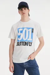 Remera blanca de algodón con cuello redondo y estampado frontal con el logo de Levi's y la inscripción "501 Buttonfly" en azul y negro.