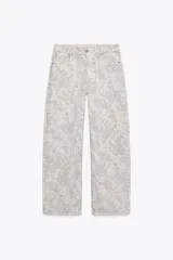 Pantalón de jean largo color crudo con estampado floral en gris, tiro medio, corte balloon y cinco bolsillos.