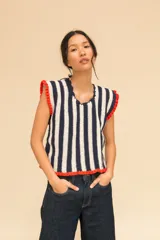 Top tejido a crochet con rayas verticales azules y blancas, cuello en V y volados rojos en los bordes.