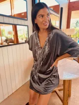 Vestido corto gris de terciopelo con escote en V y flecos de lentejuelas plateadas.