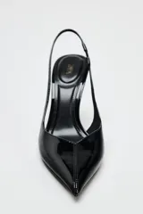 Zapato destalonado negro acharolado con tacón fino y punta. Tiene una tira trasera con elástico.