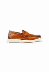 Mocasines color marrón de cuero con antifaz y suela de goma blanca.