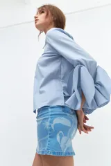 Minifalda de jean celeste con estampado de flores blancas, de corte recto y tiro alto.