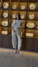 Pantalón tipo babucha color beige, de lino, con pinzas centrales, bolsillos laterales y ajuste en el tobillo.