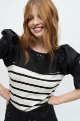 Blusa negra de tejido de punto con escote redondo y mangas cortas abullonadas con detalle de broderie.