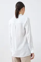 Camisa oversize celeste y blanca a rayas verticales, con cuello mao y mangas largas con puños abotonados.