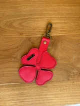 Llavero con forma de trébol de cuatro hojas color fucsia, con textura símil cuero y costuras en los bordes.