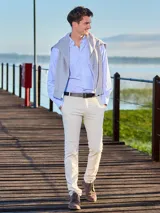 Pantalón de vestir color beige, de corte recto, con bolsillos laterales y traseros. Se ajusta a la cintura con cinturón de cuero marrón.