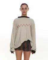 Sweater tejido color crema con bordado manual en forma de zig-zag color naranja. Terminaciones de cuello y puños en color marrón.