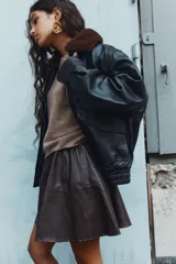 Pollera mini circular de color marrón oscuro, confeccionada en tejido revestido con efecto cuero y cintura elástica.