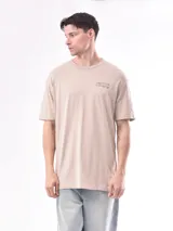 Remera beige de corte holgado con estampado de texto en el pecho.