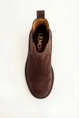 Bota tipo Chelsea de gamuza color marrón oscuro, con paneles elásticos laterales al tono, tirador trasero y suela de goma robusta con vira pespunteada.