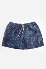 Short de baño azul con estampado de hojas de palmera en tonos azulados y blancos. Tiene cintura elástica con cordón ajustable, bolsillos laterales, tela ligera de secado rápido, suspensor interno y logo estampado en la pierna.