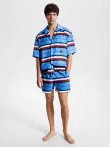 Short de baño Tommy Hilfiger con estampado de rayas horizontales en azul, blanco y rojo. Diseño con monograma TH estampado en azul sobre las rayas azules. Cintura elástica con cordón ajustable.