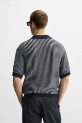 Polo de punto de algodón a rayas verticales en tonos azul marino y gris. Tiene cuello clásico, tapeta con botones y corte recto.