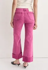 Pantalón de jean azul oscuro con corte acampanado, tiro medio y dobladillo en el ruedo. Presenta costuras marcadas en el frente y estampado abstracto en tonos grises y blancos en el interior del dobladillo.