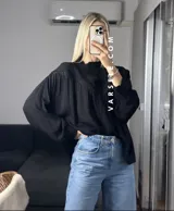 Camisa blanca de mangas largas con detalles de encaje en el cuello y en el frente.