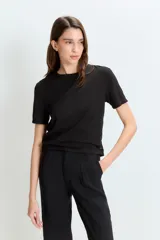 Remera negra de mangas cortas con espalda descubierta y tiras doradas de sostén a la vista.