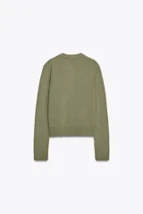 Chaqueta de punto color rosa pálido, con cuello redondo y cierre frontal de botones oscuros. Presenta mangas largas y un corte a la cintura.